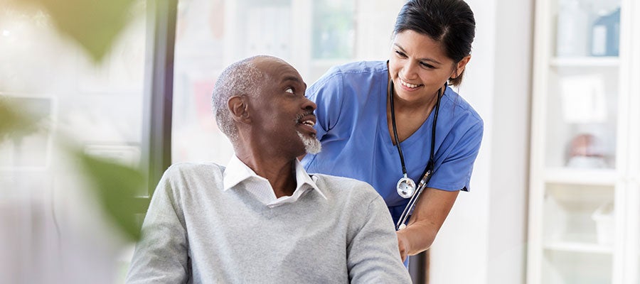 Man smiling in chair with nurse behind him