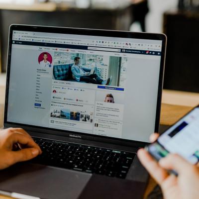 Photo of person on social media on their phone and laptop