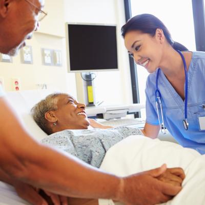 Nurse comforting elderly patient in their bed