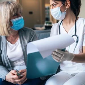 nurse and patient wearing surgical mask receiving a consult clipboard